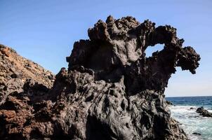 ein Felsen Formation auf das Strand mit ein Blau Himmel foto