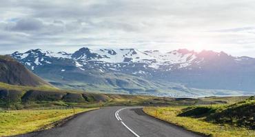 nach Island reisen. Straße in einer hellen sonnigen Berglandschaft. Vatna-Vulkan bedeckt mit Schnee und Eis auf dem Hintergrund foto