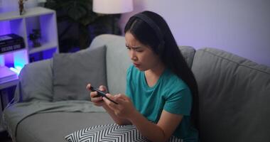 Porträt von jung asiatisch Frau ernst spielen ein online Spiel frustriert mit Verlust oder Fehler Sitzung auf Sofa im Leben Zimmer beim home.gamer Lebensstil Konzept. foto