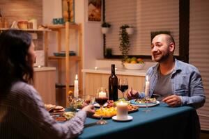 Mann erzählen ein Geschichte zu Ehefrau im Küche während festlich Abendessen. entspannen glücklich Menschen, Sitzung beim Tabelle im Küche, genießen das Mahlzeit, feiern Jahrestag im das Essen Zimmer foto