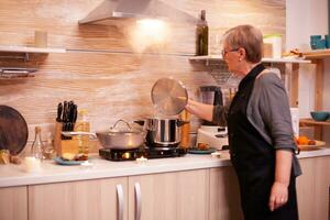 Frau vorbereiten Abendessen zum romantisch Abendessen im Küche. im Ruhestand Frau Kochen nahrhaft Essen zum ihr und Mann zu feiern Beziehung Jubiläum. foto