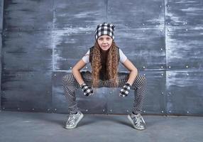 junges schönes Mädchen tanzt in trendiger Kleidung auf Grunge-Hintergrund foto
