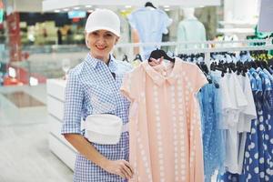 Frau Kleidung einkaufen. Shopper, der sich Kleidung im Innenbereich im Laden ansieht. schönes glückliches lächelndes asiatisches kaukasisches weibliches Modell foto