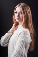 Nahaufnahme Porträt einer schönen jungen Frau in weißem Pullover und Jeans, isoliert auf schwarzem Hintergrund