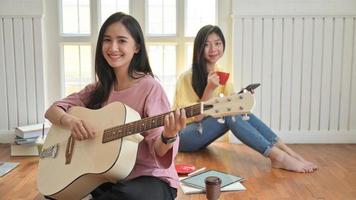 Asiatische Mädchen im Teenageralter singen und spielen Gitarre. Sie bleiben zu Hause, um den Ausbruch des Koronavirus zu verhindern.