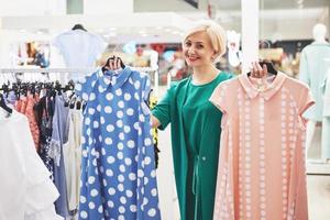 Frau Kleidung einkaufen. Shopper, der sich Kleidung im Innenbereich im Laden ansieht. schönes glückliches lächelndes asiatisches kaukasisches weibliches Modell foto