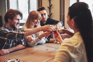 Gruppe junger Freunde, die Spaß haben und lachen, während sie im Restaurant am Tisch speisen? foto