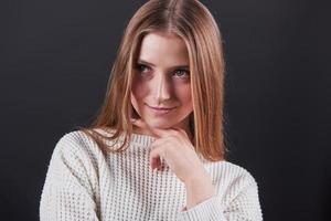 Nahaufnahme Porträt einer schönen jungen Frau in weißem Pullover und Jeans, isoliert auf schwarzem Hintergrund