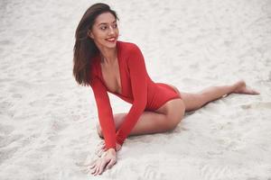 schöne junge gebräunte Frau im roten Bikini posiert am Strand. sexy Modelportrait mit perfektem Körper. Sommerurlaub Konzept foto