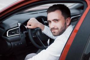 selbstbewusster junger Geschäftsmann, der am Steuer seines neuen Autos sitzt foto