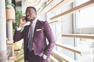 Porträt eines jungen und gutaussehenden afroamerikanischen Geschäftsmannes, der in einem Anzug am Telefon spricht