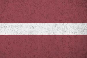 lettland-flagge in hellen farben auf alter reliefputzwand dargestellt. strukturierte Fahne auf rauem Hintergrund foto