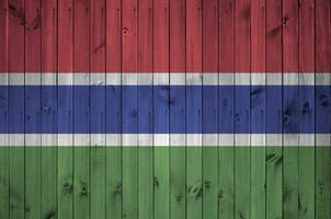 Gambia Flagge abgebildet im hell Farbe Farben auf alt hölzern Mauer. texturiert Banner auf Rau Hintergrund foto