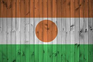 Niger Flagge abgebildet im hell Farbe Farben auf alt hölzern Mauer. texturiert Banner auf Rau Hintergrund foto