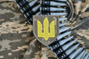 ukrainisch Heer Symbol auf Maschine Gewehr Gürtel Lügen auf ukrainisch pixelig Militär- tarnen foto