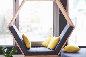 Bürolounge Innenbürogebäude oder Café, Sofastuhl in Form eines Sechsecks mit Kissen in der Nähe des Fensters foto