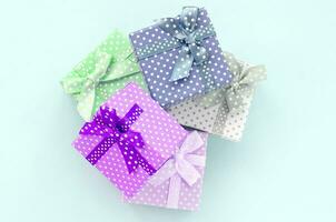 Haufen von kleinen farbigen Geschenkboxen mit Bändern liegt auf violettem Hintergrund. minimalismus flach draufsicht foto