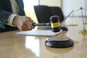 Konzept der Gerechtigkeit, Anwalt, der einen Hammer hält, der vorgibt, auf ein Holztablett zu schlagen, das auf den Schreibtisch gestellt wird. foto