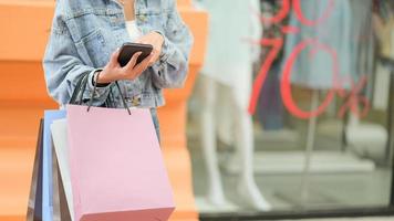 Der Shopper hält eine Papiertüte in der Hand und sucht auf seinem Smartphone nach Informationen.