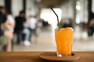 Glas Orangensaft auf einem Holztablett auf einem Tisch im Café unscharfen Hintergrund. foto