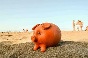 ein Orange Schweinchen Bank auf das Strand foto