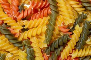 ungekocht beschwingt farbig Fusilli Pasta. ein faszinierend kulinarisch Segeltuch von mehrfarbig Spiralen, Erstellen ein lebhaft und texturiert Hintergrund zum Gourmet Kochen. farbig trocken Pasta. roh Makkaroni foto