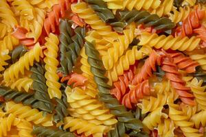 ungekocht beschwingt farbig Fusilli Pasta. ein faszinierend kulinarisch Segeltuch von mehrfarbig Spiralen, Erstellen ein lebhaft und texturiert Hintergrund zum Gourmet Kochen. farbig trocken Pasta. roh Makkaroni foto