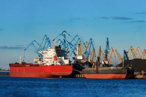 rot Ladung Schiff Wird geladen im das Hafen von Riga, Europa foto