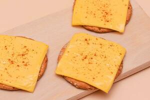 knusprig Cracker Sandwiches mit Käse und Paprika auf hölzern Schneiden Tafel und Beige Hintergrund foto