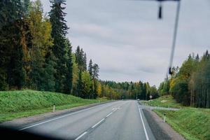 Blick auf die Straße und den herbstlichen Wald durch das Busfenster. Ausflug foto