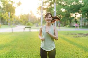 passen asiatisch jung Frau Joggen im Park lächelnd glücklich Laufen und genießen ein gesund draussen Lebensstil. weiblich Jogger. Fitness Läufer Mädchen im Öffentlichkeit Park. gesund Lebensstil und Wellness Sein Konzept foto