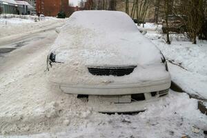 Schnee Entfernung Nachwirkungen Auto bedeckt im Schnee auf ein Winter Straße foto