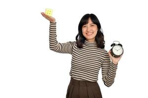 asiatisch Frau halten Alarm Uhr und Puzzle Würfel Stehen auf Weiß Hintergrund. lösen kubisch Probleme, Problem Lösung und Herstellung strategisch bewegt sich Konzept foto