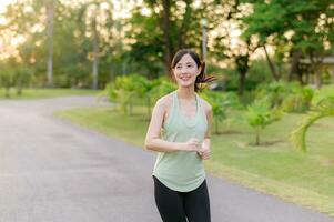 passen asiatisch jung Frau Joggen im Park lächelnd glücklich Laufen und genießen ein gesund draussen Lebensstil. weiblich Jogger. Fitness Läufer Mädchen im Öffentlichkeit Park. gesund Lebensstil und Wellness Sein Konzept foto