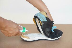 Nahansicht Mann Hand verwenden Super kleben zu Fix gebrochen Schuh. Konzept, Reparatur zum Wiederverwendung oder recyceln Schuhe Vor Sein Müll. foto