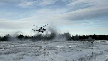 Hubschrauber Landung auf ein schneebedeckt Feld mit das Wald und wolkig Himmel auf das Hintergrund. Clip. erziehen groß Schneesturm während Landung auf ein Winter Feld. foto
