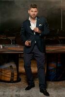 erfolgreich jung Mann mit Glas von Whiskey zeigen Paar von Asse in der Nähe von Poker Tabelle im Kasino foto