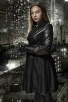 retro Porträt von nicht zugänglich schön Frau im schwarz Mantel steht gegen das Hintergrund von das Nacht Stadt. Film noir. Jahrgang Hollywood Stil. Studio Schuss. foto