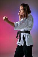 sportlich Frau im traditionell Kimono ist üben Karate im Studio. foto