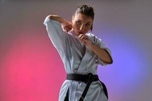 sportlich Frau im traditionell Kimono ist üben Karate im Studio. foto