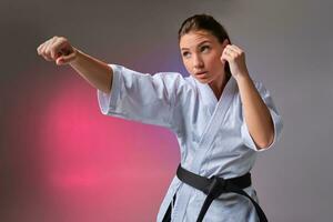 sportlich Frau im traditionell Kimono ist üben Karate im Studio. foto