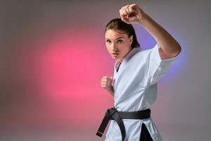 sportlich Frau im traditionell Kimono ist üben Karate im Studio. foto