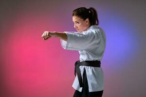 sportlich Frau im traditionell Kimono ist üben Karate im Studio. foto