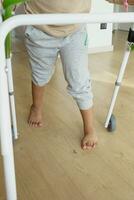 Kind mit Gehen Rahmen und Knie Orthese beim Zuhause foto