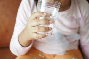 Kind Hand halten ein Glas von Wasser foto