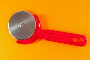 ein Pizza Cutter mit ein rot Griff foto