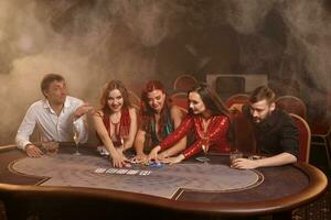 Gruppe von ein jung reich freunde sind spielen Poker beim ein Kasino. foto