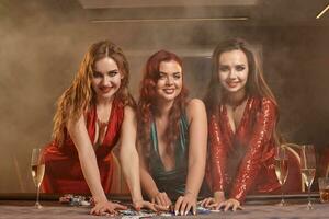 drei schön jung Frauen sind spielen Poker beim ein Kasino. foto