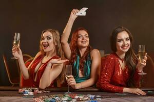 drei schön jung Frauen sind spielen Poker beim ein Kasino. foto