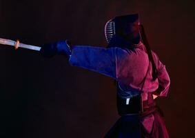 schließen oben Schuss, Kendo Kämpfer tragen im ein Rüstung, traditionell Kimono, Helm üben kriegerisch Kunst mit shinai Bambus Schwert, schwarz Hintergrund. foto